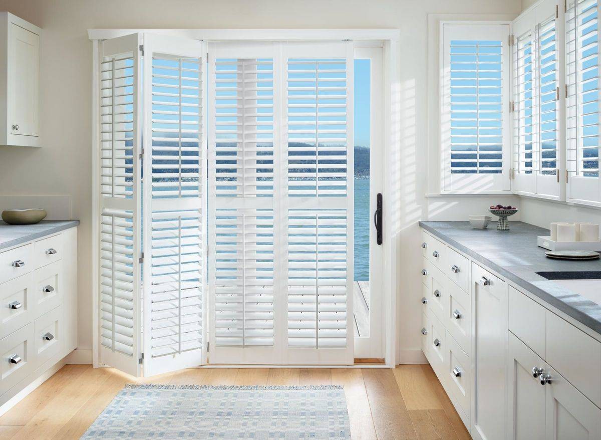 A home kitchen sliding glass door equipped with Hunter Douglas Palm Beach™ Polysatin™ Vinyl Shutters