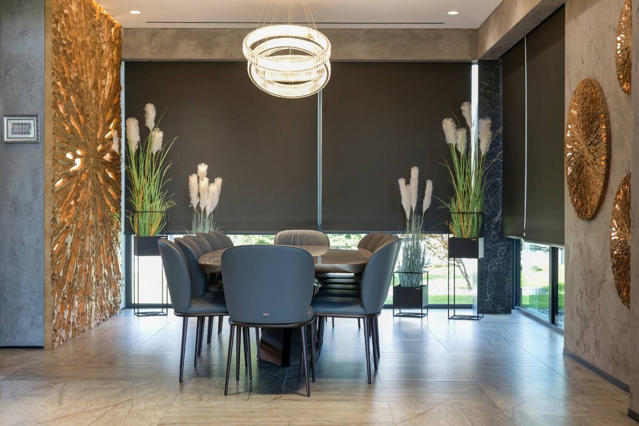 Blackout roller shades half down on large windows in an elegant, modern dining room at Design 5 Ltd. near Honolulu, HI